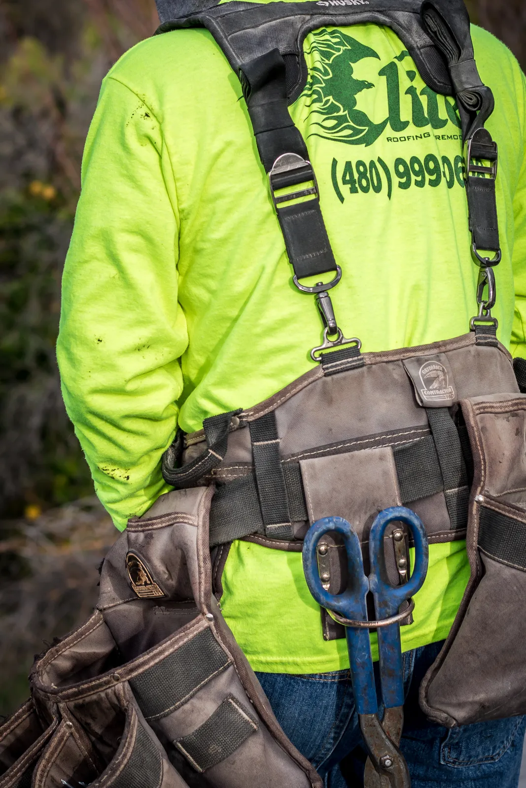 Elite Roofing and Remodeling roofer in safety harness and tool belt