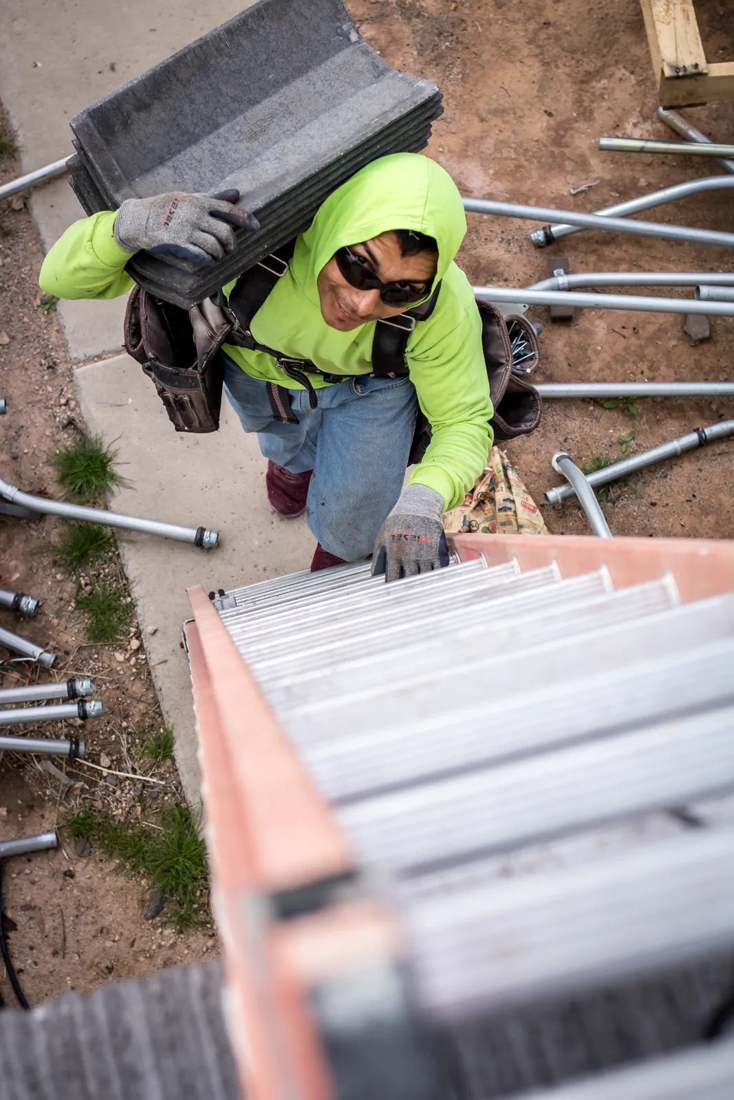 Elite roofer carrying roof tiles up a ladder during a roof replacement in Arizona